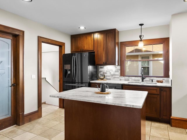 kitchen with tasteful backsplash, hanging light fixtures, light tile patterned flooring, black fridge with ice dispenser, and a sink