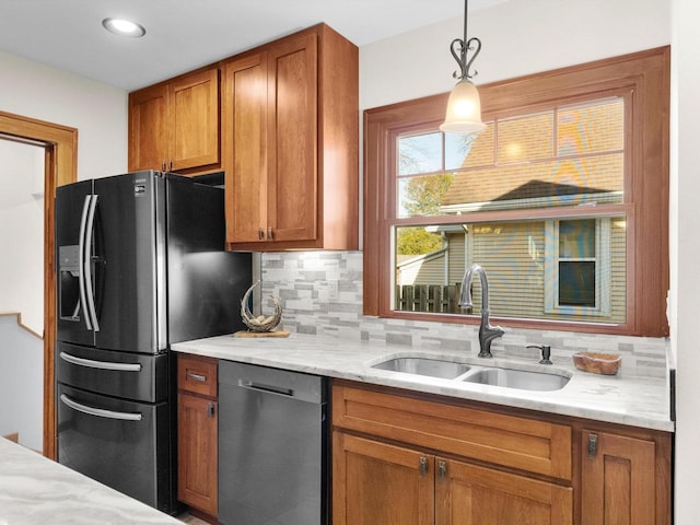 kitchen featuring a sink, decorative backsplash, dishwasher, brown cabinets, and black fridge