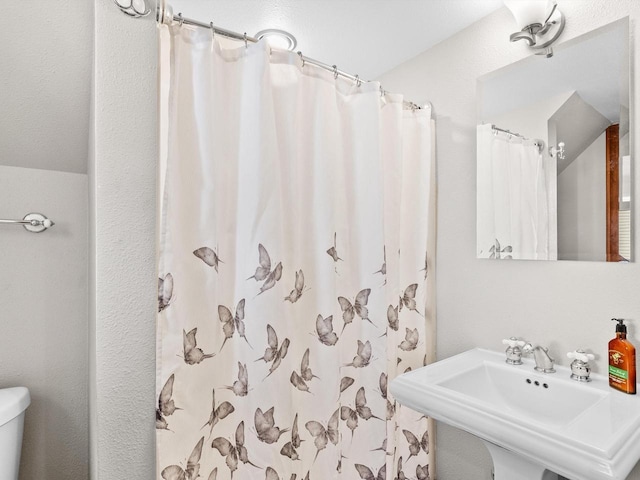 full bathroom featuring curtained shower, toilet, and a sink