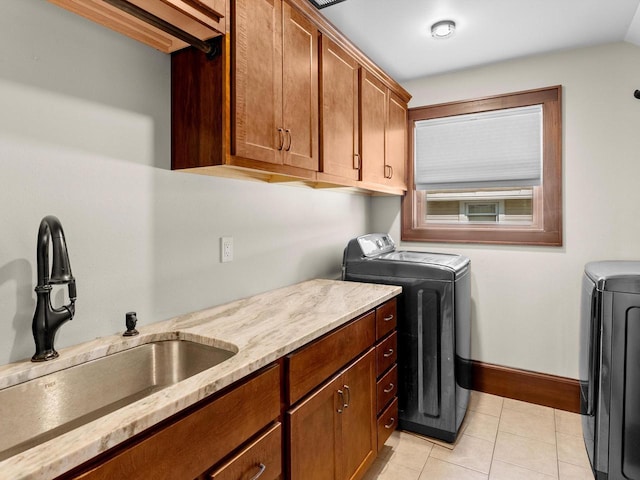 clothes washing area featuring baseboards, light tile patterned flooring, cabinet space, a sink, and washer and dryer