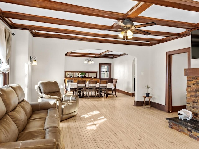 living room featuring beam ceiling, light wood-style flooring, ceiling fan with notable chandelier, arched walkways, and baseboards