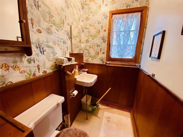 bathroom featuring wainscoting, wallpapered walls, toilet, and a sink