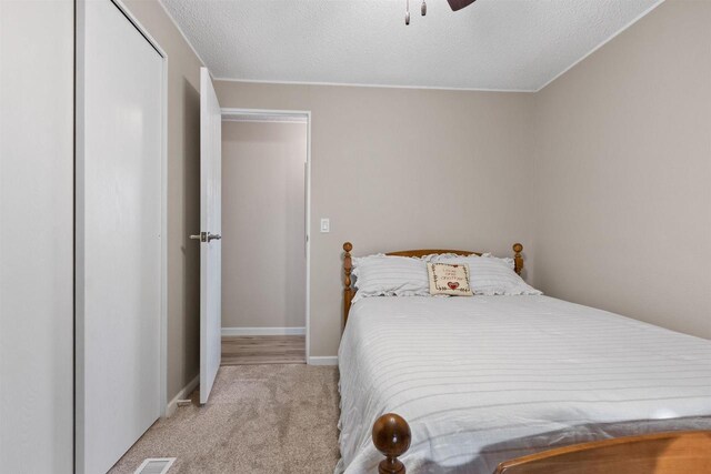 bedroom with baseboards, a textured ceiling, ceiling fan, and carpet flooring