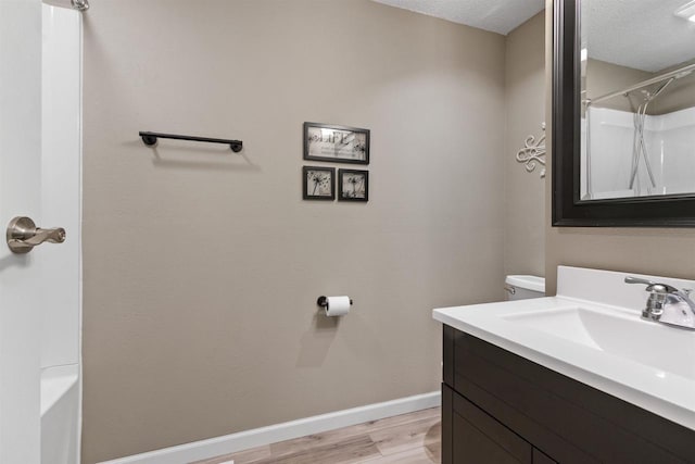 full bath featuring a textured ceiling, wood finished floors, baseboards, and a shower