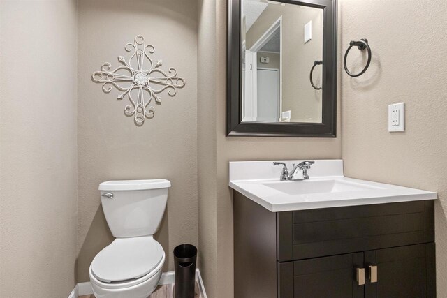 bathroom with toilet, vanity, and baseboards