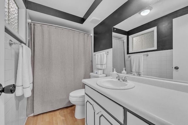 full bath featuring toilet, tile walls, vanity, and wood finished floors