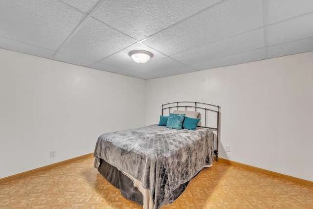 bedroom featuring a drop ceiling and baseboards