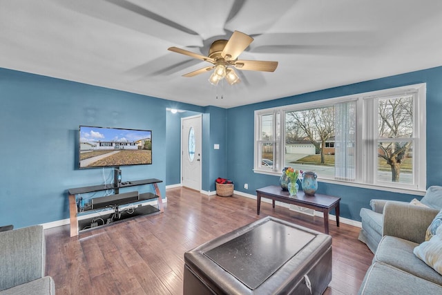 living area with a ceiling fan, baseboards, and wood finished floors