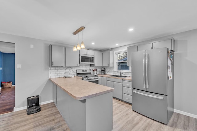 kitchen featuring appliances with stainless steel finishes, light countertops, gray cabinetry, and a sink