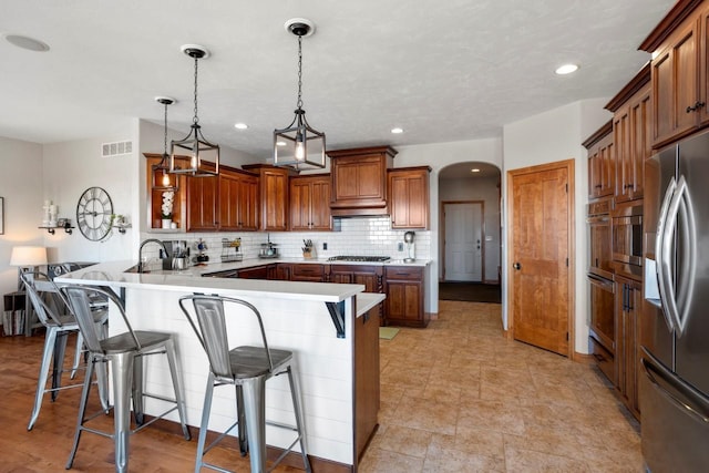 kitchen with visible vents, a peninsula, arched walkways, stainless steel appliances, and backsplash