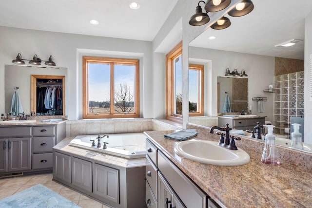 bathroom with a sink, two vanities, a whirlpool tub, and tile patterned flooring