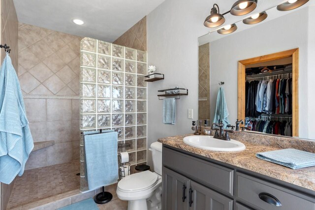 bathroom with toilet, a spacious closet, vanity, and a walk in shower