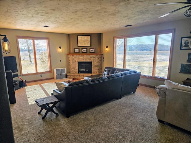 carpeted living room featuring a wealth of natural light, a textured ceiling, and a brick fireplace