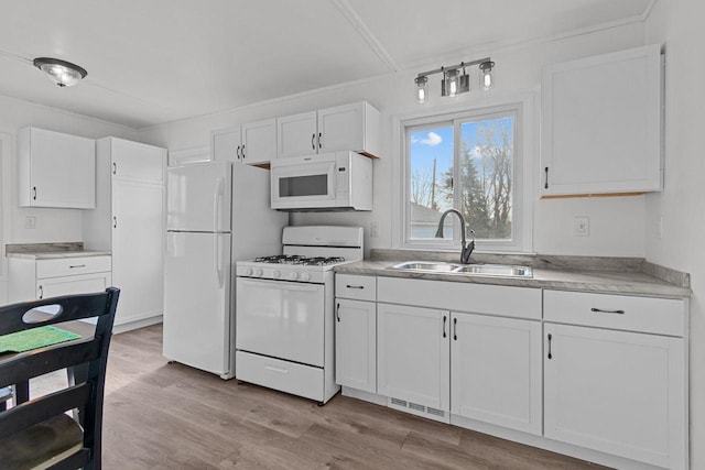 kitchen with white appliances, a sink, light countertops, white cabinetry, and light wood-type flooring