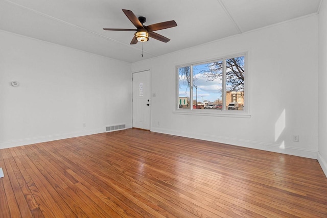 empty room featuring visible vents, baseboards, hardwood / wood-style floors, and a ceiling fan