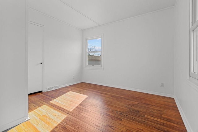 empty room featuring visible vents, baseboards, and hardwood / wood-style floors