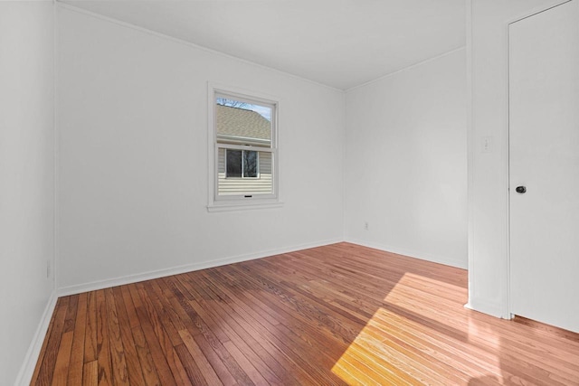 spare room featuring baseboards and wood-type flooring