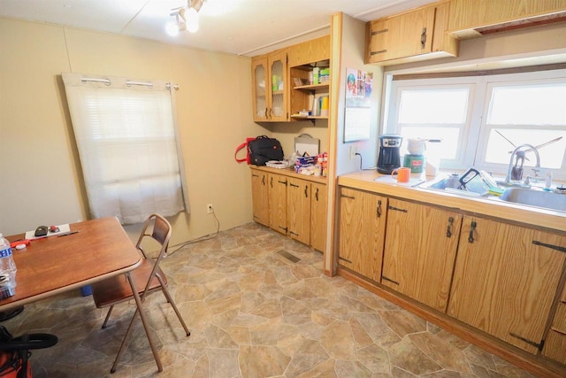 kitchen featuring stone finish floor, open shelves, light countertops, and a sink