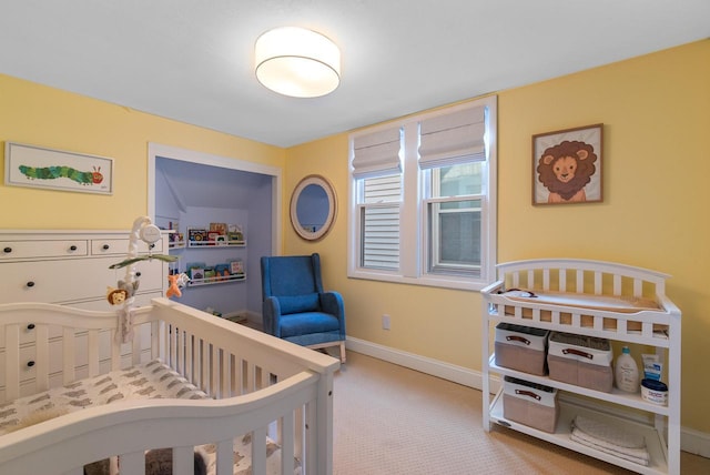 bedroom with baseboards, carpet, and a nursery area