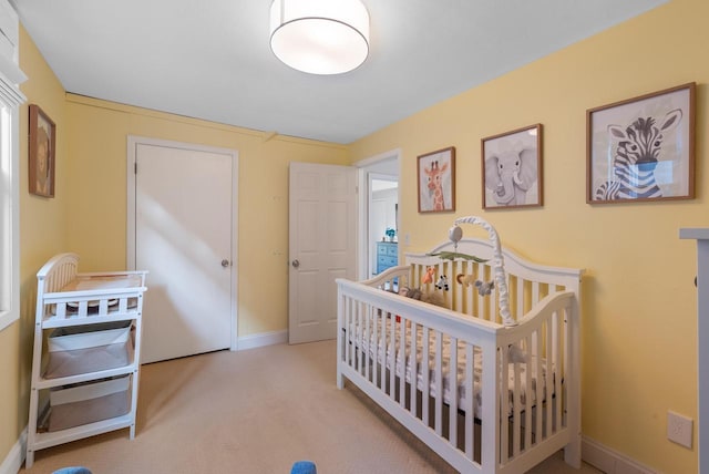 bedroom with carpet flooring, a nursery area, and baseboards