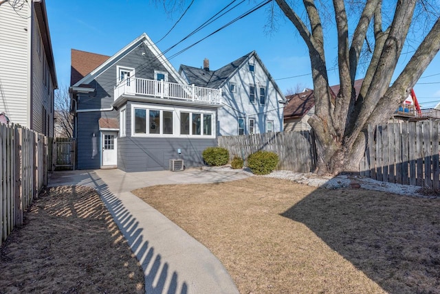 rear view of property with a fenced backyard, a patio area, a lawn, and a balcony