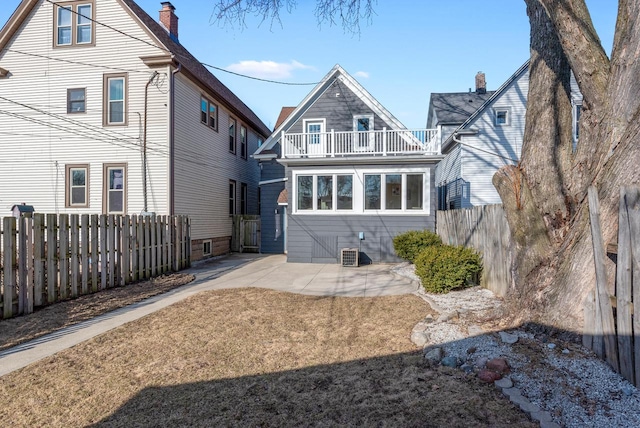 rear view of house with a patio area, a balcony, and fence