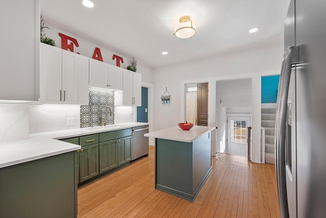 kitchen featuring a sink, a center island, stainless steel appliances, white cabinets, and green cabinetry