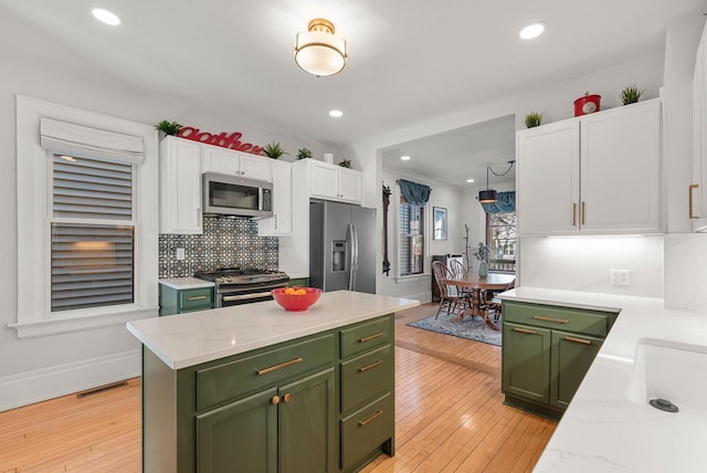 kitchen with visible vents, backsplash, white cabinetry, appliances with stainless steel finishes, and green cabinets