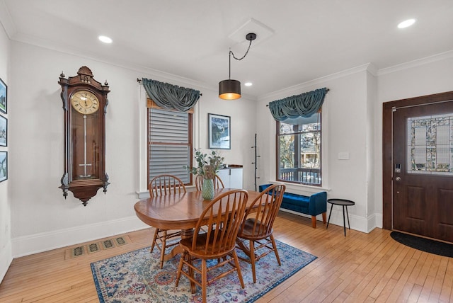 dining room featuring light wood-type flooring, visible vents, baseboards, and ornamental molding