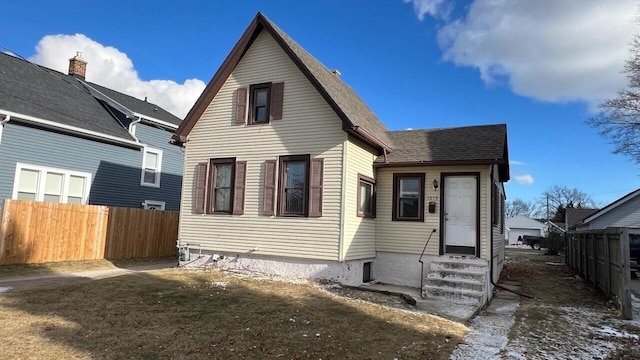 view of front of house with entry steps, fence, and roof with shingles