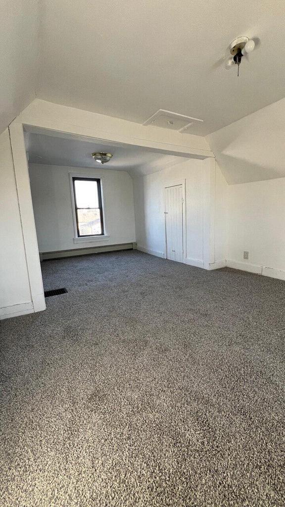 additional living space featuring vaulted ceiling, baseboards, visible vents, and carpet floors