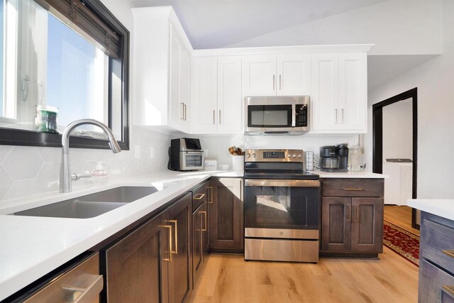 kitchen featuring a sink, white cabinetry, stainless steel appliances, light wood finished floors, and light countertops