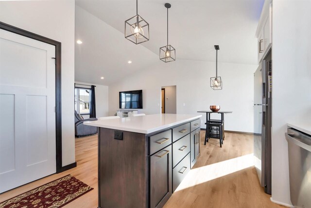 kitchen featuring a kitchen island, pendant lighting, light countertops, light wood-style floors, and stainless steel appliances