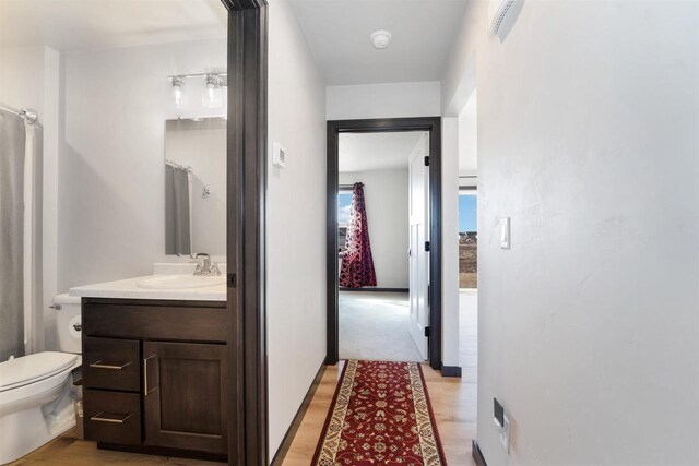 hallway featuring light wood-style floors and a sink