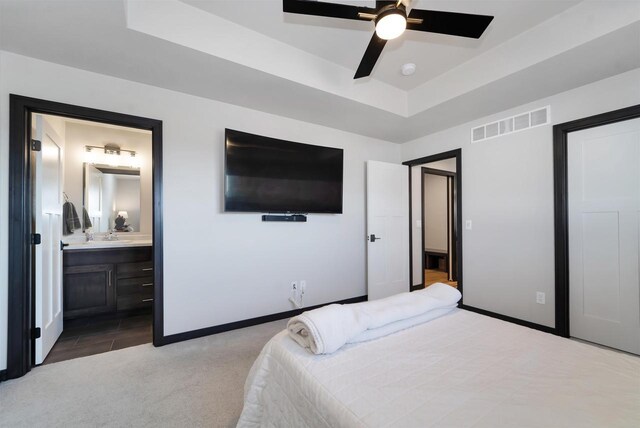 carpeted bedroom with a tray ceiling, visible vents, baseboards, and ceiling fan