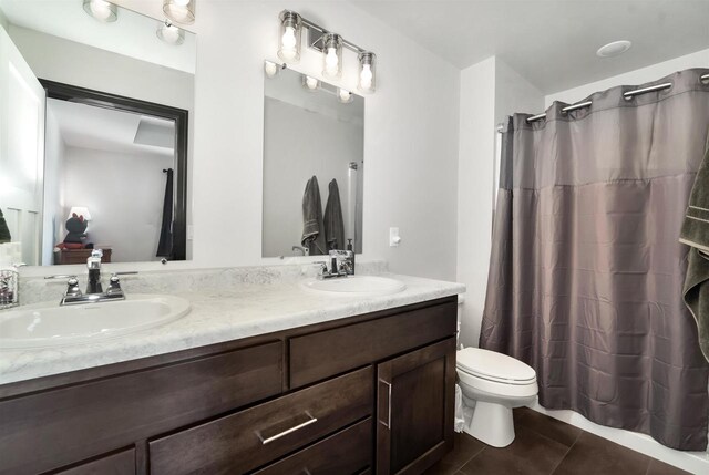 bathroom featuring a sink, toilet, double vanity, and tile patterned flooring