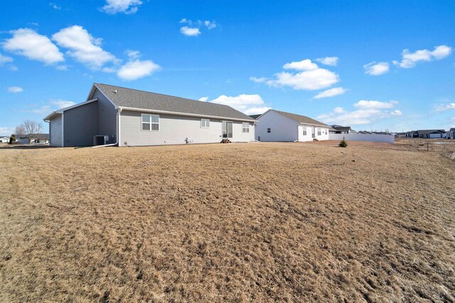 rear view of property with central AC and a yard