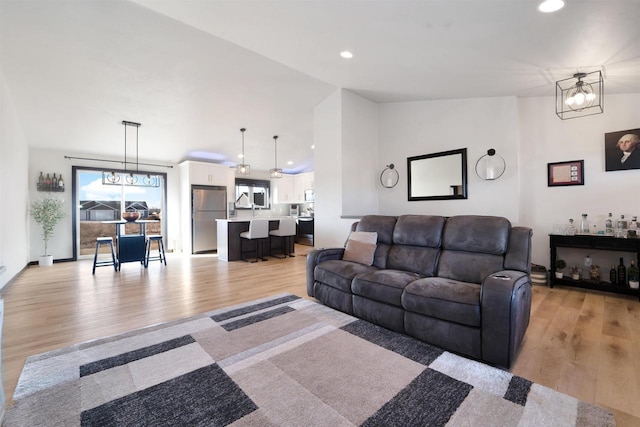 living room featuring recessed lighting, light wood-type flooring, an inviting chandelier, and vaulted ceiling