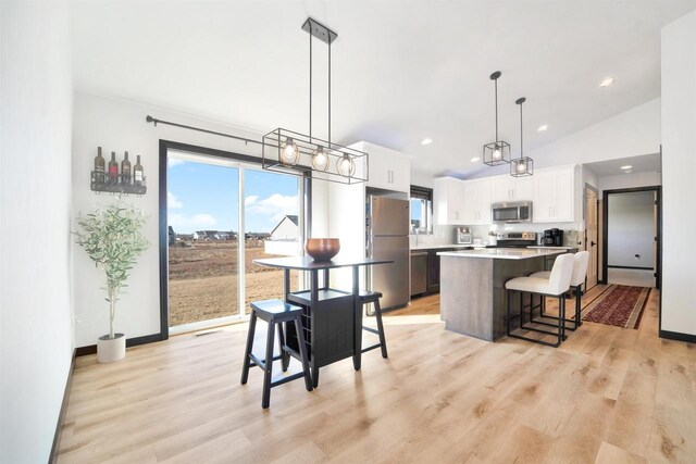 kitchen featuring a kitchen island, white cabinetry, stainless steel appliances, a breakfast bar area, and light countertops