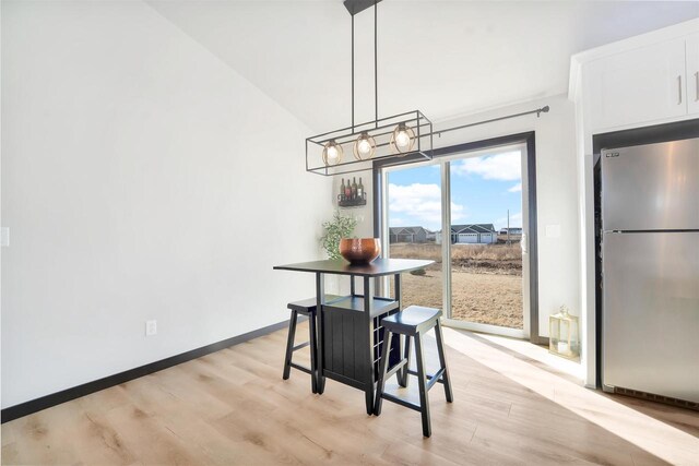 dining room with a notable chandelier, baseboards, and light wood finished floors