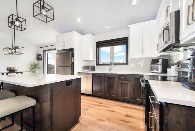 kitchen featuring a sink, light wood-style floors, appliances with stainless steel finishes, a breakfast bar area, and light countertops