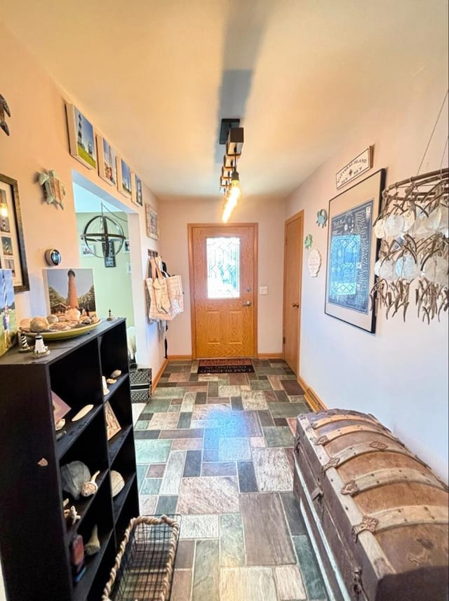 foyer entrance with stone finish floor and baseboards