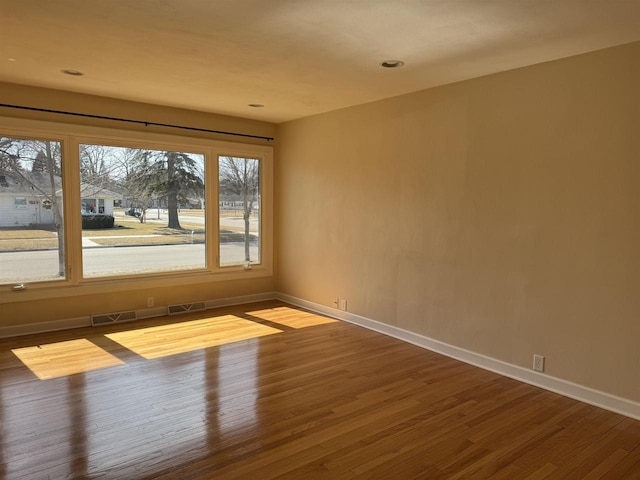 empty room with visible vents, baseboards, and wood finished floors