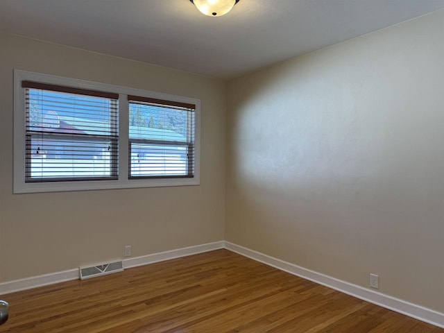 unfurnished room featuring wood finished floors, visible vents, and baseboards