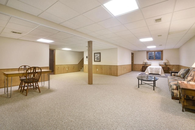 living area featuring visible vents, wood walls, and wainscoting