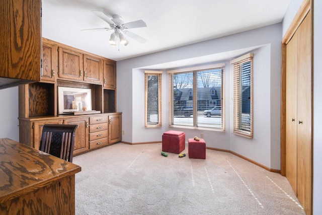 home office featuring ceiling fan, baseboards, and light carpet