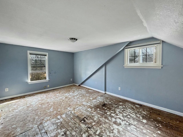 unfurnished room with a textured ceiling, baseboards, and vaulted ceiling