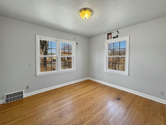 spare room with visible vents, baseboards, and wood-type flooring