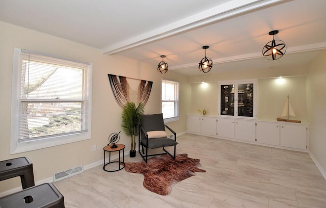 sitting room with visible vents, beam ceiling, and baseboards