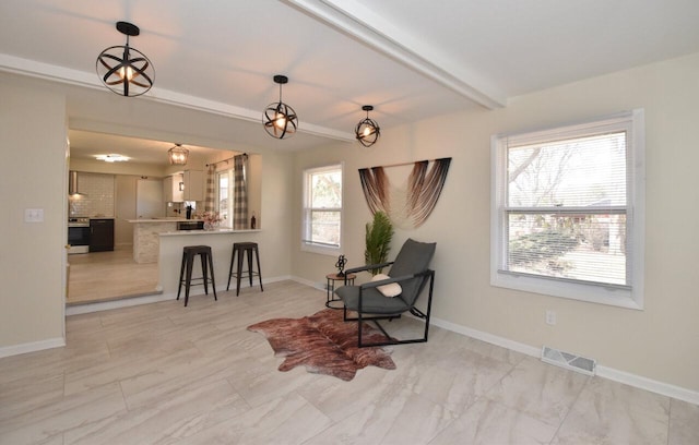 living area featuring beamed ceiling, baseboards, and visible vents